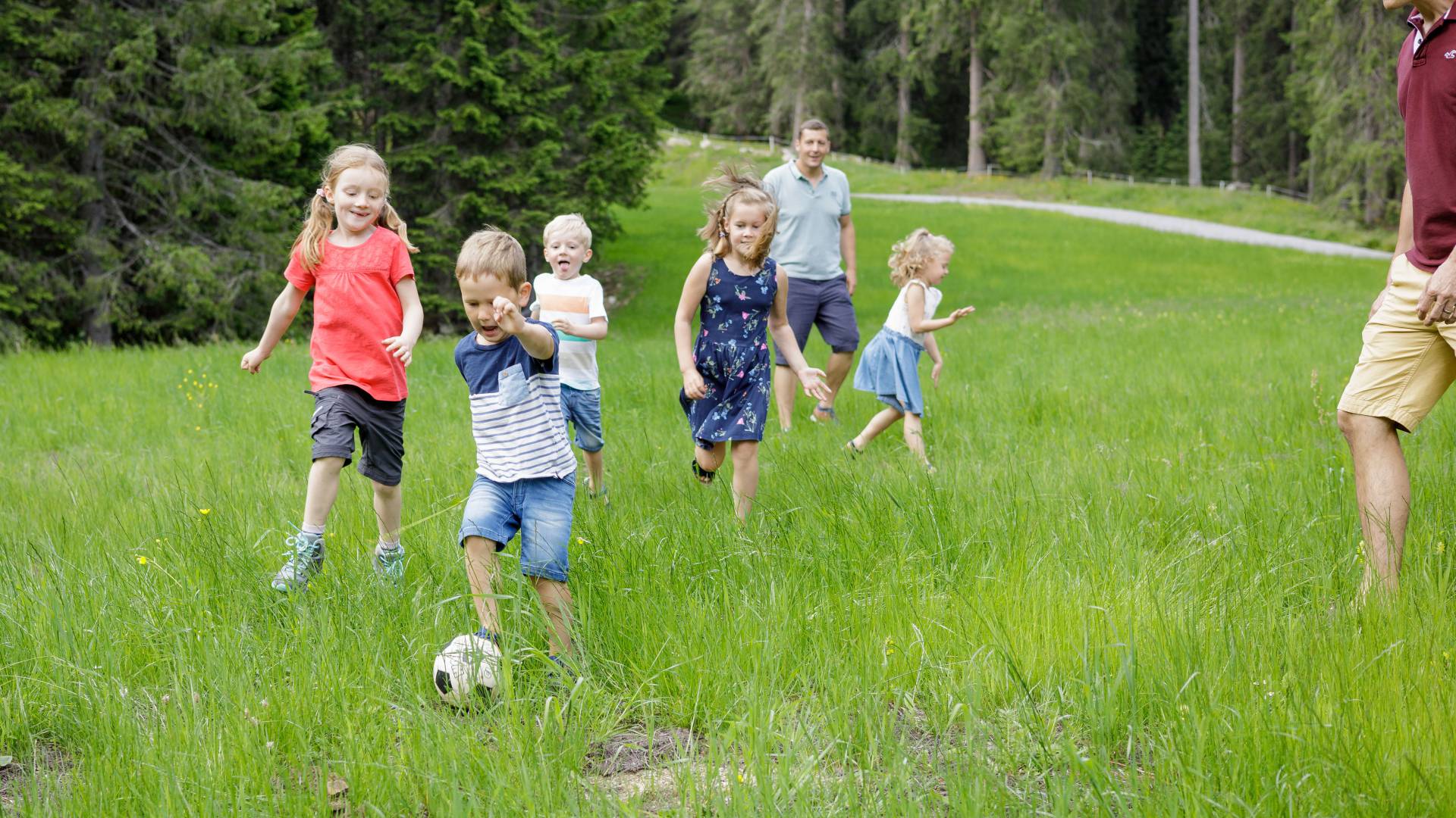 Kinder spielen auf grüner Wiese Fußball