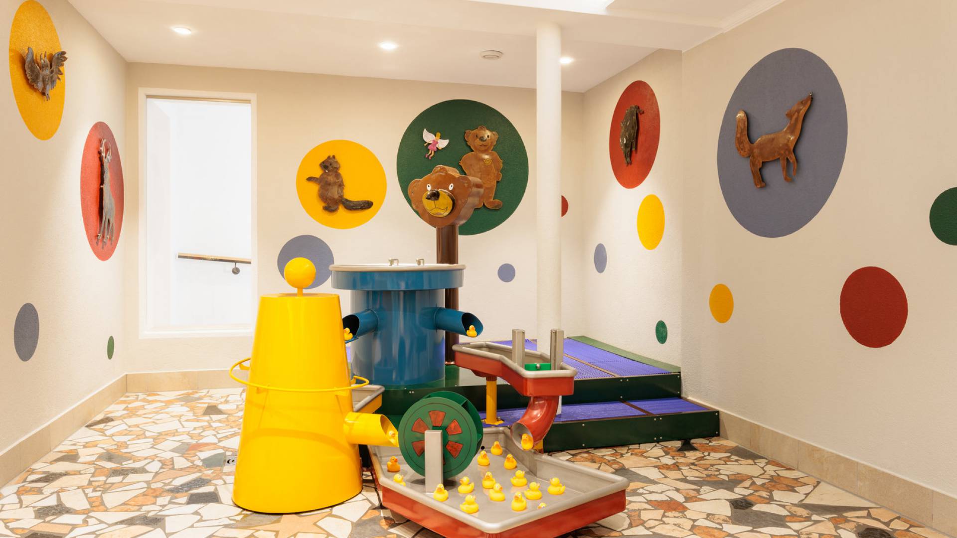 Wasserspiel im Babybereich der Wasserwelt mit bunten Farbkeisen an den Wänden, auf denen die Tiere des Waldes abgebildet sind. Das Wasserspiel ist ideal für kleine Entdecker im Kindergartenalter gedacht. 