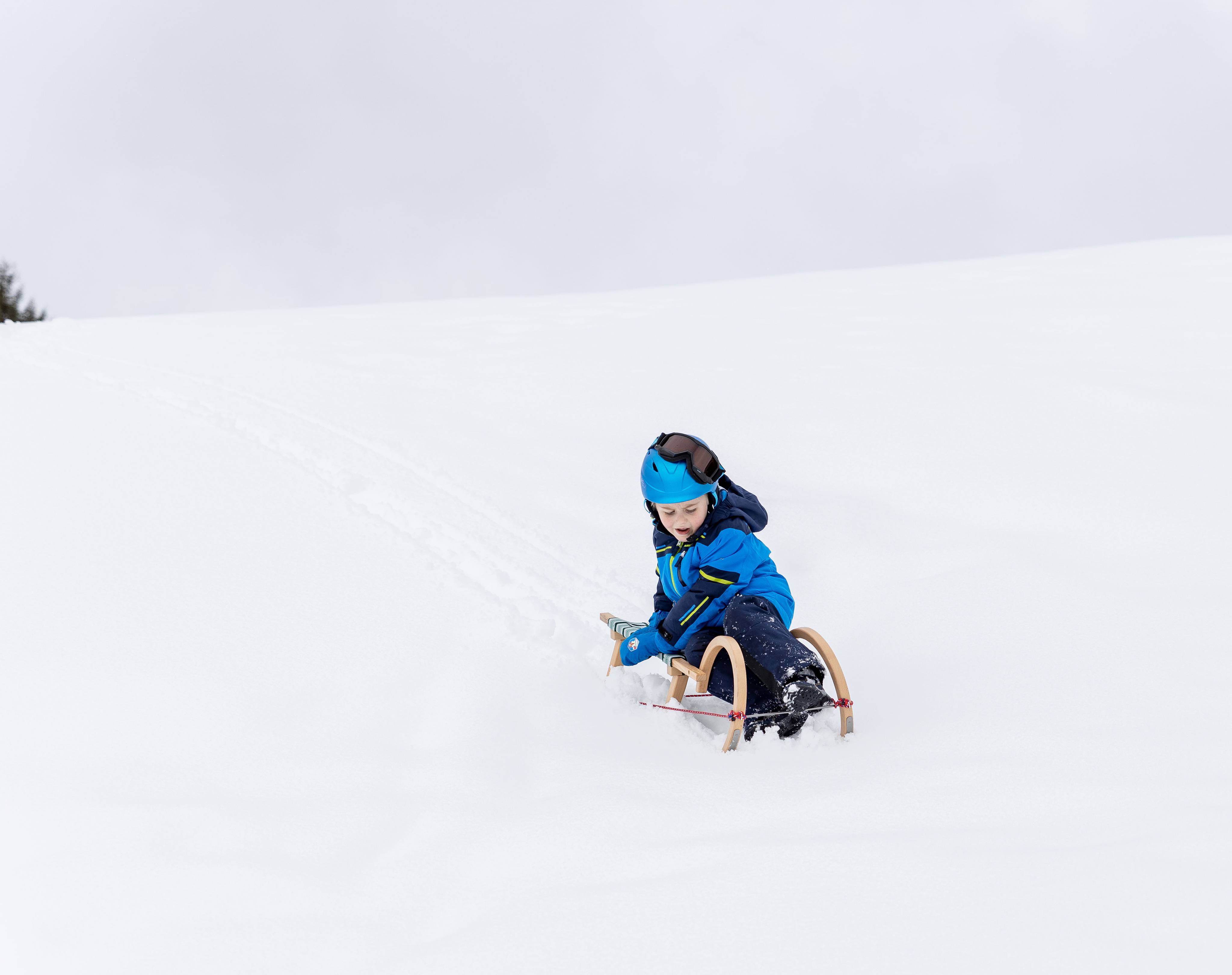 Child riding down the snowy mountain on a sledge in Tyrol