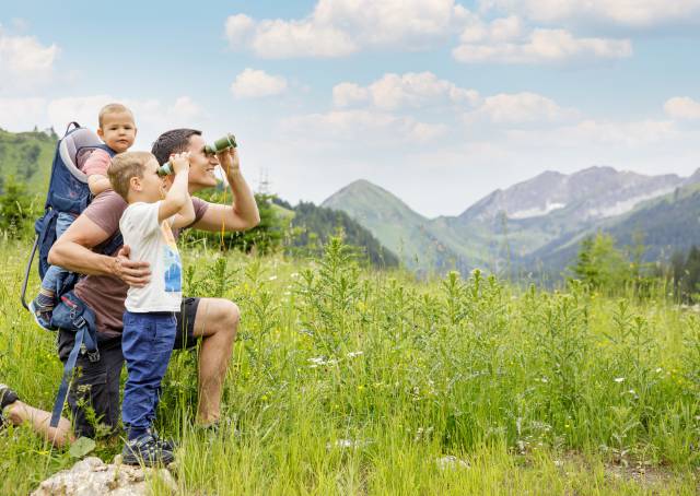 Family looks through binoculars at the Tyrolean Alps