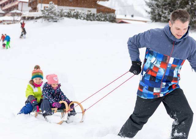 Father with children on a sled with his children in the snow