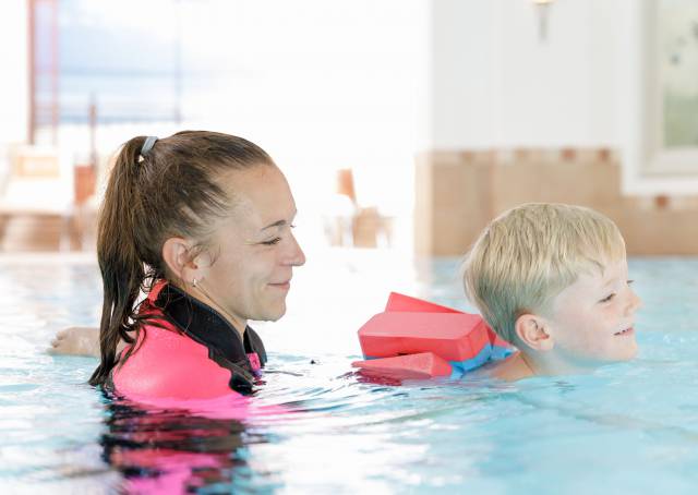 Swimming instructor with child in the pool during a children's swimming course at the Familotel Kaiserhof in Tyrol