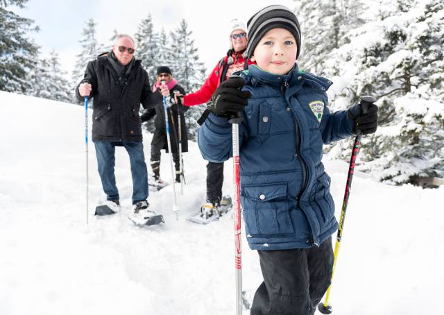 Familie mit Kind und Großerltern beim Schneeschuhwandern in Tirol