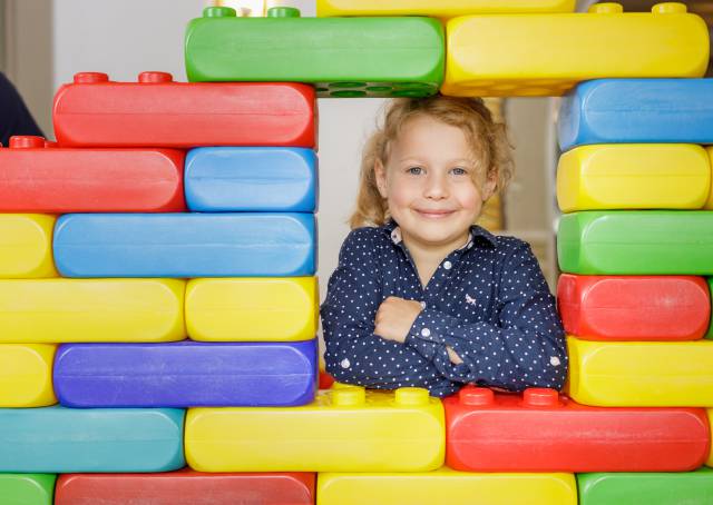 Child looks through large Lego wall