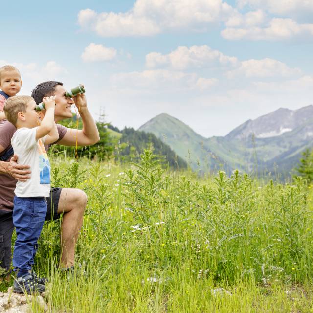 Family looks through binoculars at the Tyrolean Alps