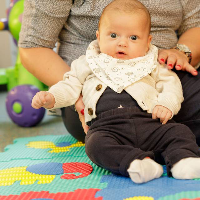 Baby sits on play mat