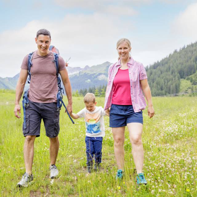 Parents with son hike across meadow in Berwang