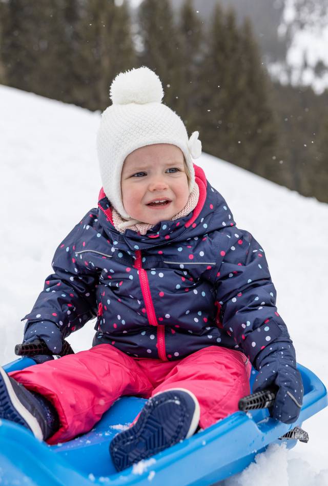 Child sitting on a sledge in the snow in Tyrol