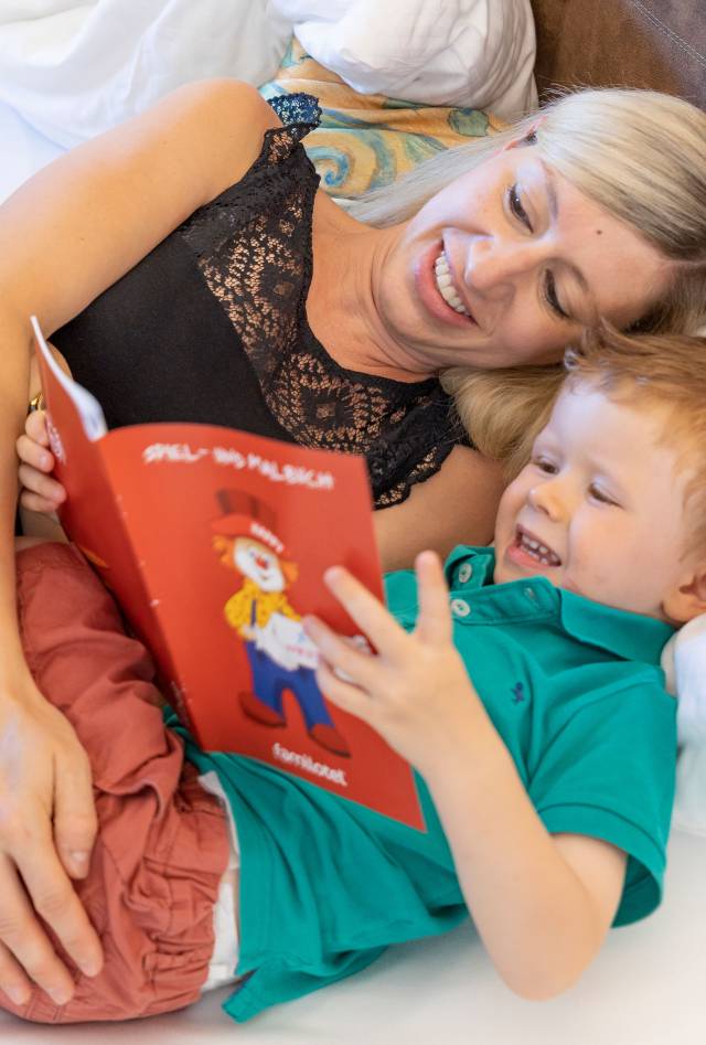 Mother with son in bed reading a book