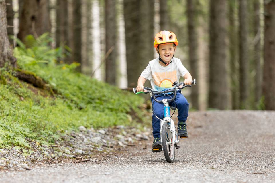 Boy riding his child's bike in the forest