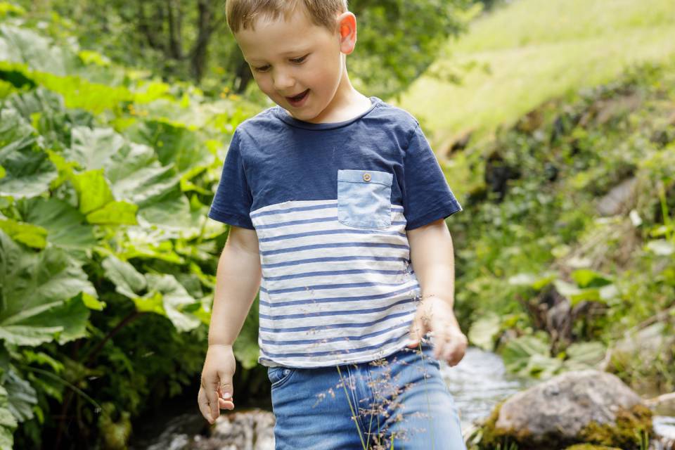 Boy runs through forest stream in Tyrol