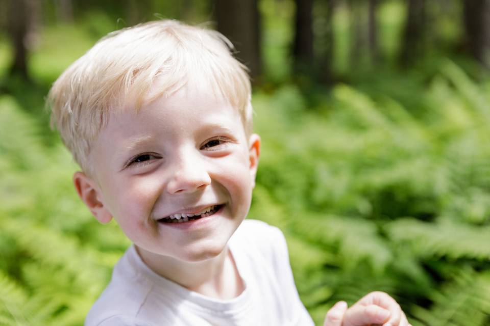 Boy grins and stands in the forest