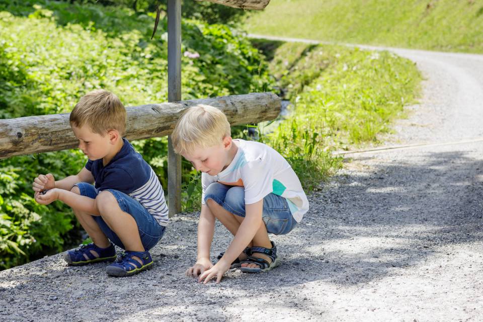 Two boys collecting stones on a bridge in Tyrol