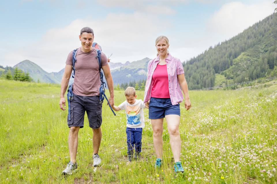 Parents with son hike across meadow in Berwang