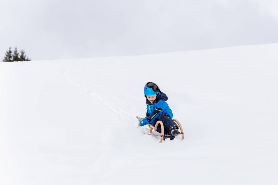 Child riding down the snowy mountain on a sledge in Tyrol