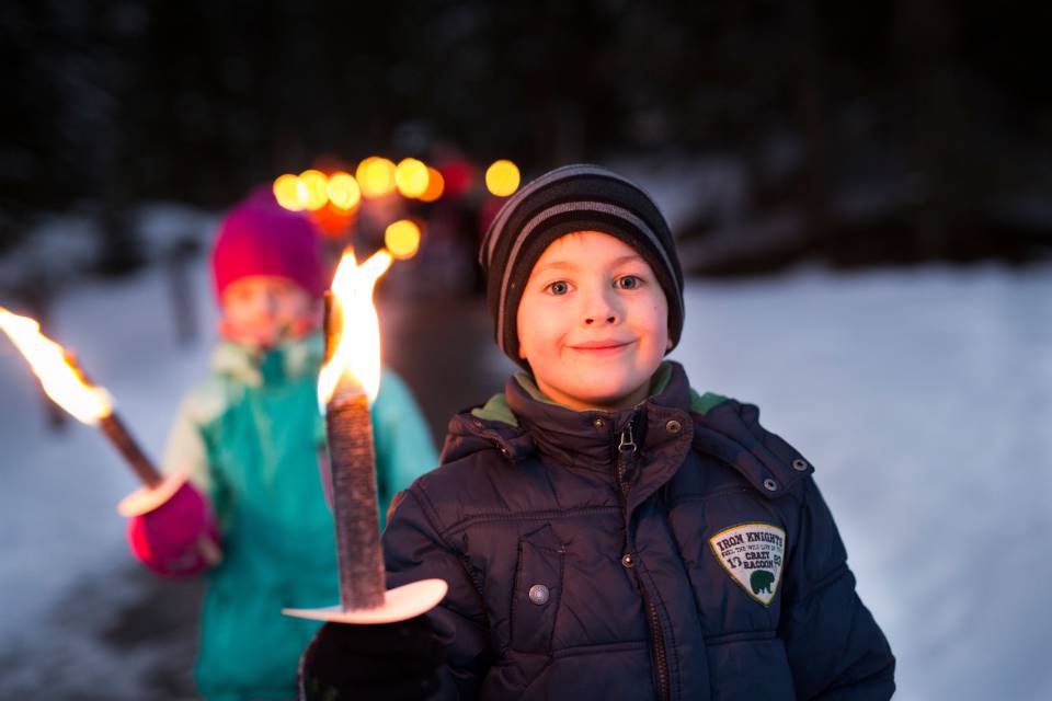 Boy holding a torch and walking through the snow