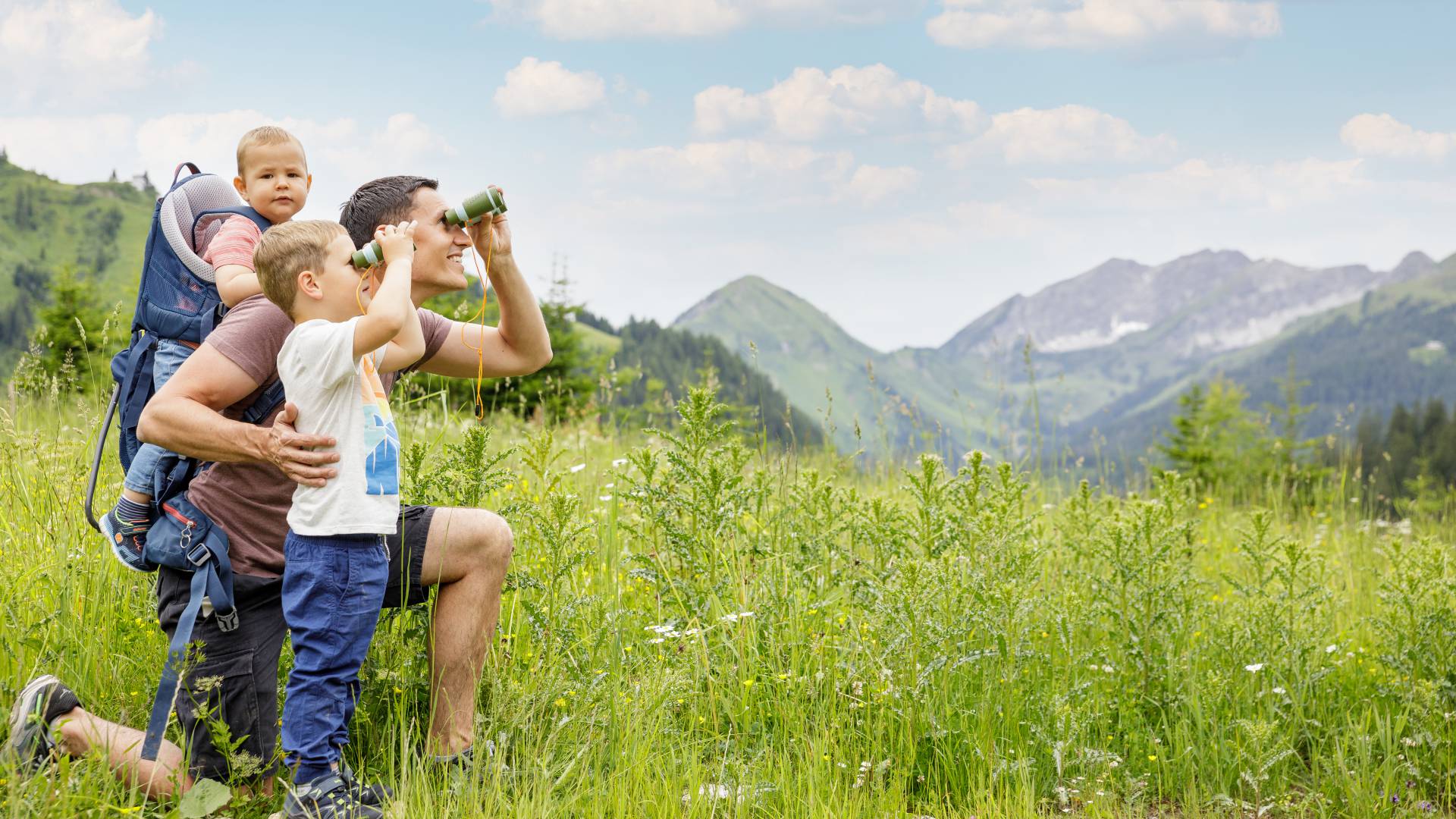 Family looks through binoculars at the Tyrolean Alps