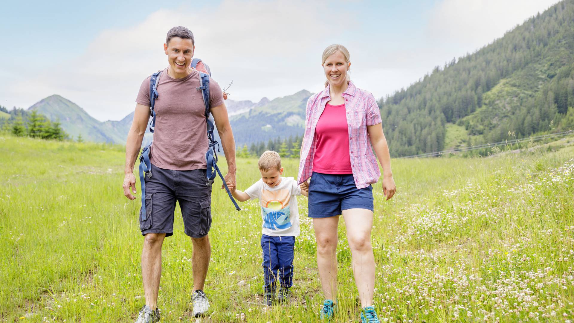 Parents with son hike across meadow in Berwang