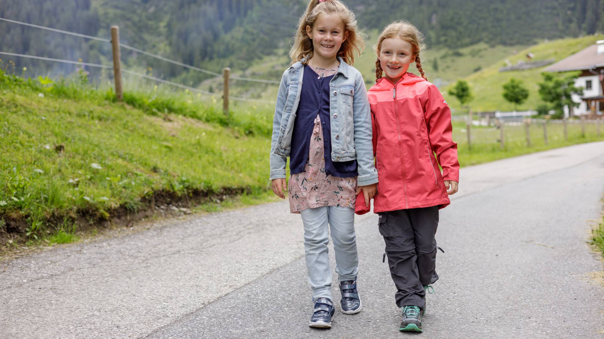 Girls running down a street along meadows