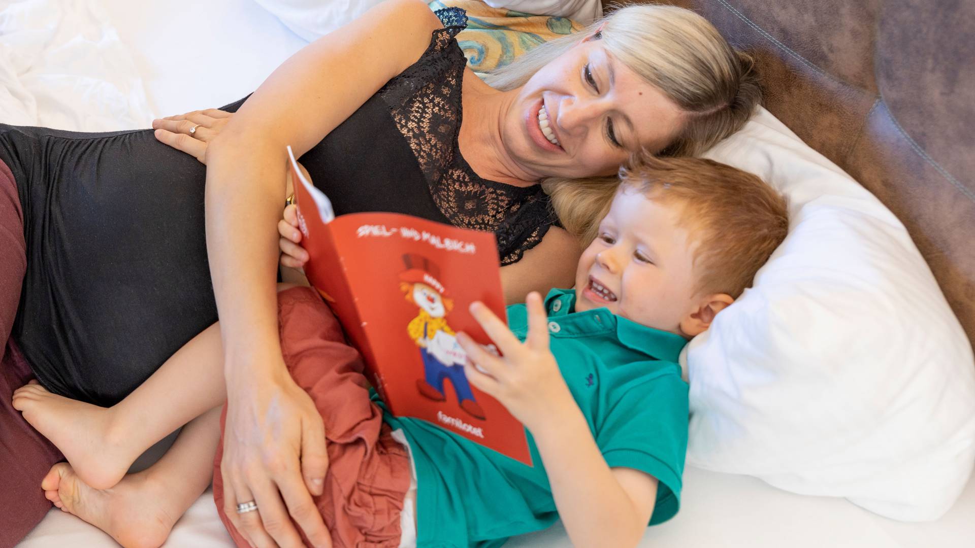 Mother with son in bed reading a book